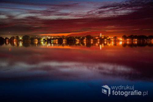 Nocna panorama z widokiem na miasto i jego odbiciem w jeziorze Chodzieskim.