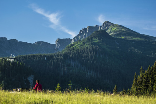 Zdjęcie przedstawiające turystkę na polanie Kalatówki spoglądającą na szczyt Kasprowego Wierchu