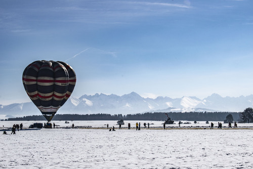 Balon prezentujący się na tle Tatr podczas zawodów w lotach balonem na lotnisku w Nowym Targu - zima 2021
