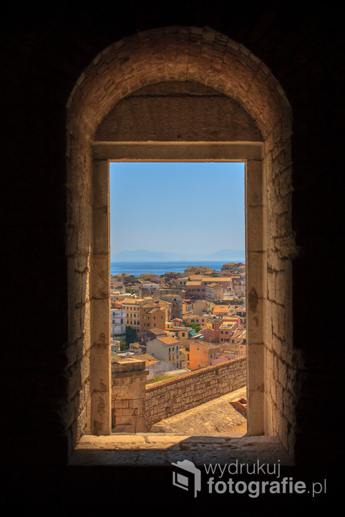 Każdy, kto choć raz odwiedził Grecję lub jakąkolwiek Grecką wyspę, zakochuje się w tym klimacie. Widok przez okno na starożytne miasto Korfu.