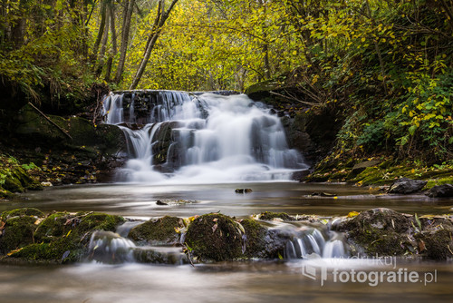Pięknie położony wodospad na małej rzece w Bieszczadach w Dołżycy oraz otaczający jesienny las.