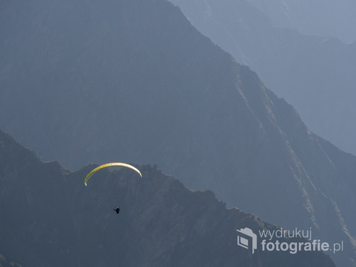 Paralotniarz. Jedno z moich ulubionych zdjęć z Alp francuskich. Paralotniarstwo jest tam niesamowicie popularnym sportem. Na zdjęciu samotny paralotniarz oraz perspektywa górskich zboczy, 