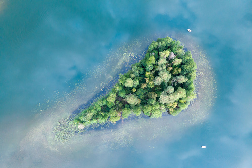 Wyspa na jeziorze Kalejty z lotu ptaka.Obok wyspy widoczne łodzie.