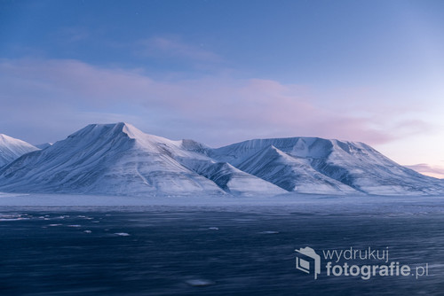 Zdjęcie wykonane w styczniu, w trakcie nocy polarnej w Longyearbyen, tysiąc kilometrów od bieguna północnego. Co prawda o tej porze roku słońce tam nie wschodzi, ale przybliża się na tyle do horyzontu, żeby rozświetlić niebo pastelowymi barwami.