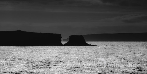 Czarno-białe klify półwyspu Baleal, które majestatycznie i spokojnie wystają ponad taflę wody.