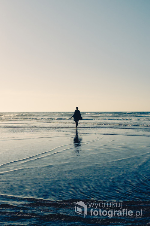 Kobieta chodząca wzdłuż wybrzeża podczas odpływu.