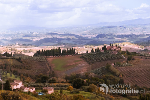 Typowy krajobraz toskański widziany z San Gimignano..Pierwszy plan pogrążony w cieniu, drugi plan w słońcu, które uwypukla Apeniny pod niebieskim niebem.