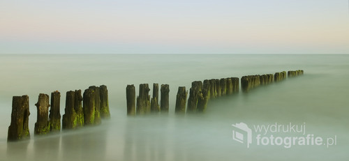 Długi czas ekspozycji rozmył wody Bałtyku otulając nimi stare falochrony. Fotografia wykonana w czasie letniego wypoczynku, o świcie.   