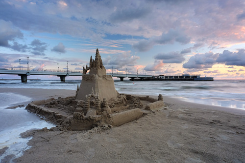 Zamek z piasku ,na plaży w Kołobrzegu, w pięknych barwach wschodzącego słońca.