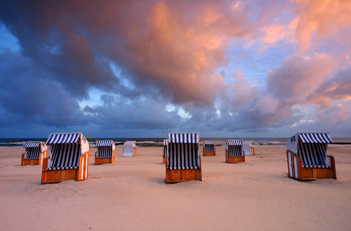 Bałtycka plaża o wschodzie słońca, kosze plażowe czekają na spragnionych słońca turystów, Kołobrzeg, Polska.
