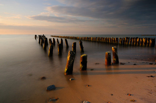 Falochron na wybrzeżu Morza Bałtyckiego, w ciepłym świetle zachodzącego słońca, Kołobrzeg, Polska