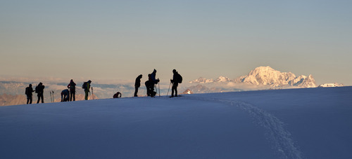 Fotografia wykonana podczas wschodu słońca na lodowcu Felik. Złociste promienie słońca, przebijające się przez chłodne powietrze poranka, delikatnie oświetlają szczyty gór, tworząc niepowtarzalny spektakl światła i cienia. Alpejski lodowiec Felik, staje się w takich momentach niemal magicznym miejscem, gdzie czas zdaje się zatrzymać, a piękno przyrody objawia się w pełnej krasie.
W tle, majestatycznie wyłaniający się Mont Blanc, najwyższy szczyt Alp i Europy Zachodniej, dodaje scenerii nie tylko wielkości, ale również pewnego rodzaju spokoju. Jego pokryte śniegiem zbocza, oświetlone pierwszymi promieniami słońca, zdają się lśnić, tworząc kontrast z ciemniejszymi partiami krajobrazu. Obecność Mont Blanc na fotografii podkreśla nie tylko fizyczną wielkość gór, ale również ich niezmierzoną moc i piękno, które inspiruje ludzi od wieków.
Taka fotografia to nie tylko zapis chwili – to opowieść o nieustannej zmianie, o cyklu dnia i nocy, o sile natury, która niezmiennie fascynuje i przyciąga. Każdy, kto spojrzy na ten obraz, może poczuć chłód poranka na lodowcu i ciepło promieni słońca, zdolne rozwiać każdą mgłę. To przypomnienie, że w naszym szybkim i często zatłoczonym świecie istnieją miejsca, gdzie czas płynie inaczej, a piękno przyrody pozostaje niezmienne.