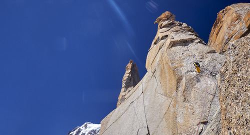 Wspinaczka na Petit Capucin, w masywie Mont Blanc, to wyzwanie, które przyciąga pasjonatów alpinizmu z całego świata. Granitowe ściany Petit Capucin, tworzące morze granitu, są marzeniem dla każdego miłośnika wspinaczki skalnej. Płyty, poprzecinane pęknięciami umożliwiają wspinaczom pokonywanie kolejnych metrów tej imponującej formacji skalnej. Pomarańczowe skały, o niezwykłej strukturze, nie tylko stanowią wyzwanie techniczne, ale również zachwycają swoją naturalną pięknością, tworząc malowniczy krajobraz, który jest tłem dla wspinaczkowych zmagań.
Umiejętności i odwaga to kluczowe cechy, które musi posiadać każdy, kto decyduje się na zdobycie Petit Capucin.  Fotografia przedstawia wspinacza asekurującego partnera, podchodzącego z dołu. To nie tylko sport, ale również sposób na życie, który uczy pokory wobec natury i buduje niezwykłe, życiowe więzi między ludźmi, którzy razem stawiają czoła wyzwaniom.
