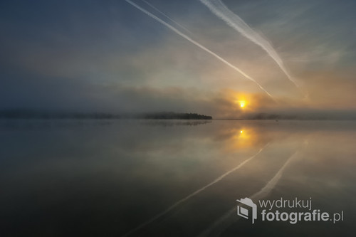 Fotografia została wykonana 18 czerwca 2011 w Bartnym Dole nad jeziorem Wigry - w dniu moich urodzin. Przed wschodem zalegała gęsta mgła i nie zapowiadało się na nic spektakularnego, ale gdy tylko wzeszło słońce mgła przerzedziła się i rozpoczął się spektakl...
