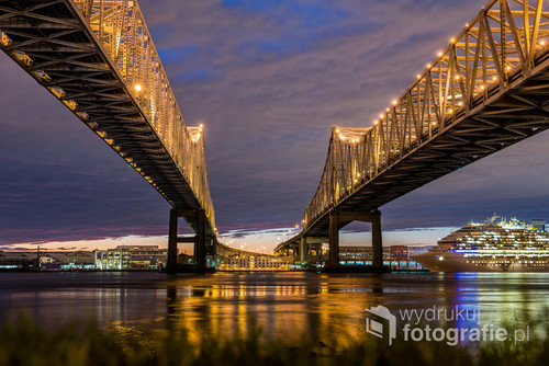Zdjęcie zostało zrobione w styczniu 2016 roku, podczas wyprawy autem przez USA.  Rzeka Missisipi dzieli Nowy Orlean na część północną i południową.  Crescent City Connection, czyli mosty je łączące, są uznawane za piąte co do długości mosty na świecie. 
Zdjęcie jest częścią wystawy 