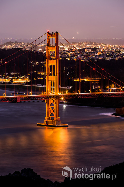 Zdjęcie wykonane w 2015 roku w Stanach Zjednoczonych. Przedstawia jeden z najsłynniejszych mostów świata - Golden Gate Bridge. W tle widać panoramę San Francisco. 
