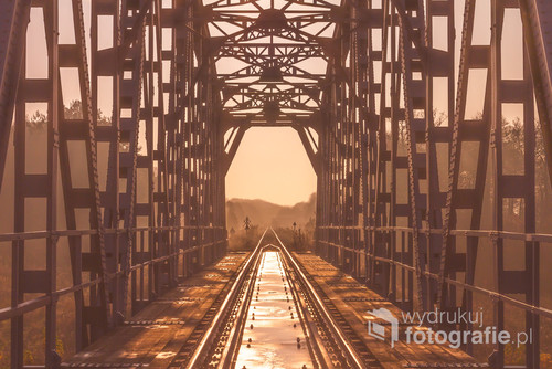 Most kolejowy nad rzeką Brok, prawym dopływem rzeki Bug. 
Gdy słońce już wstało i ruszyło w podróż nad horyzontem ja stałem już z aparatem i rozstawionym statywem na torach. Była niedziela, a ruch kolejowy milczał.