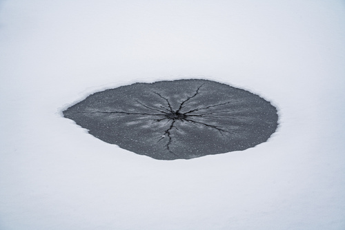 Tajemnicze, przekrwione, lodowe oko zaśnieżonego stawu