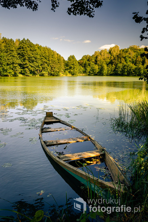Zdjęcie powstało podczas wędrówki po Suwalskim Parku Krajobrazowym, nad jeziorem ukrytym wśród wzgórz, gdzie stara łódka zacumowana przy brzegu pięknie wtapiała się w krajobraz.