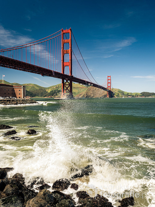 Widok na most Golden Gate w San Francisco z poziomu fal rozbijających się o nabrzeże.