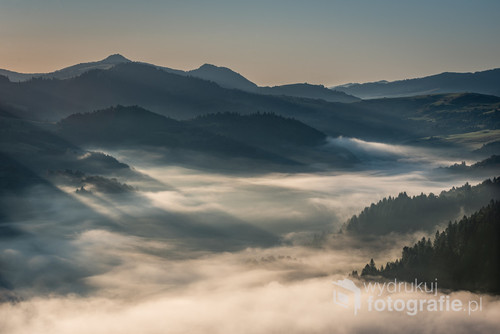 Promienie wschodzącego słońca rozświetlają mgły i chmury zawieszone w dolinie Dunajca.