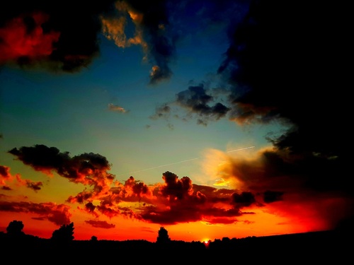 Zdjęcie zostało zrobione na wsi, latem gdy siedziałam z znajomymi przy ognisku. Zdjęcie przedstawia ładny zachód słońca, niebo jest pokryte chmurami plus to tego leci miedzy nimi samolot.