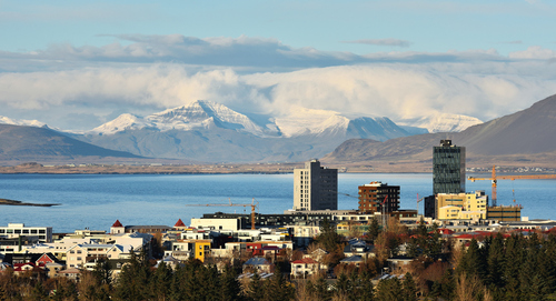 Panorama stolicy Islandii z widokiem na zatokę i ośnieżone góry na horyzoncie. 