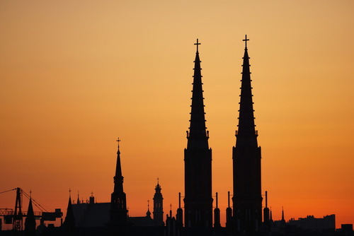 Zarysy wież Bazyliki katedralnej św. Michała Archanioła i św. Floriana Męczennika na warszawskiej Pradze na tle pomarańczowego nieba po zachodzie słońca.