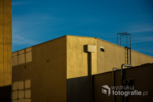 Fotografia została zrobiona w Gdańsku, w dzielnicy Morena. Zwróciłam uwagę na to, jak oświetlony jest budynek, w jaki sposób pada światło, podkreśla geometrie detali. Do tego kolor nieba ciekawie współgra z kolorem żółtym budynku. Zdecydowanie padające światło było przyczyną zrobienia tego zdjęcia. 