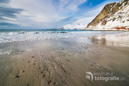 Sand beach by the cold sea with snowy peaks in the background Tromso, Norway