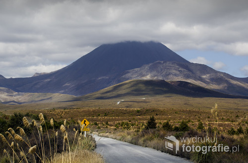 Zdjęcie przedstawia drogę do Parku Narodowego Tongariro w Nowej Zelandii. Między innymi w parku tym zostały nakręcone obie trylogie Tolkiena. Kraina aktywnych wulkanów i księżycowych krajobrazów. W tle Wulkan Ngauruhoe 2291mnpm