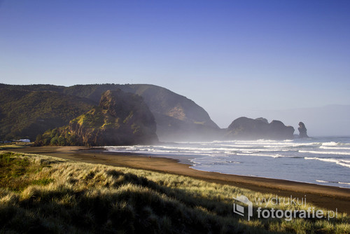Piha Beach. Plaża niedaleko Auckland w Nowej Zelandii. Na plażę przyjeżdża mnóstwo surferów gdyż są tam idealne warunki do tego sportu. Bardzo rozległa, piaszczysta ze skałą po środku o nazwie Lion Rock. 