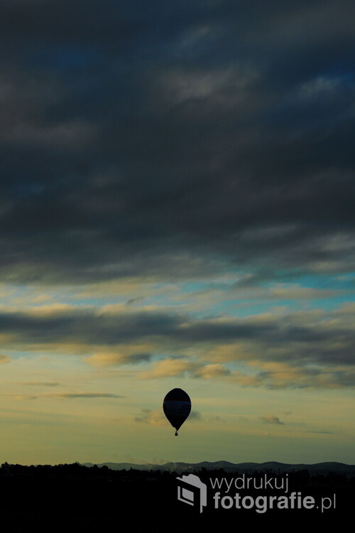 Pod dachem z chmur, tuż nad lotniskiem, wznosi się majestatycznie balon, swym powolnym ruchem przywołujący romantyczne skojarzenia. Balon nad Krosnem.