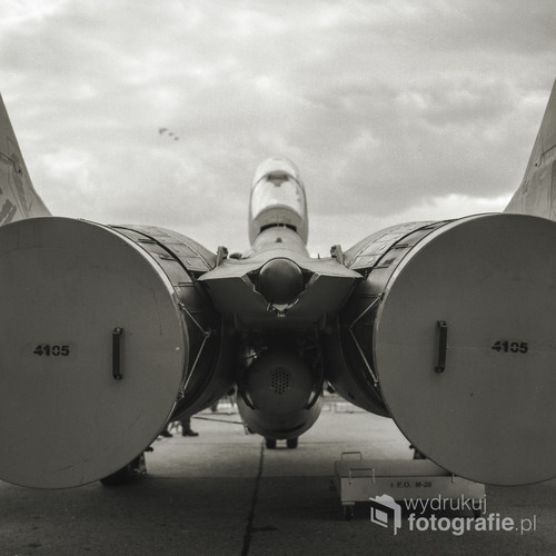 Zdjęcie wykonane podczas Radom AirShow, który odbył się w sierpniu 2015 roku. Na zdjęciu widoczny jest dwumiejscowy szkolno-bojowy MiG-29UB nr 4105, którego patronem jest Generał Stanisław Skalski. W tle widać klucz samolotów wykonujących akrobacje powietrzne. Nieoczywista perspektywa nie przeszkadza zauważyć mocy tkwiącej w tej maszynie. Zdjęcie wykonane średnioformatowym aparatem analogowym Yashica Mat 124G, na filmie KODAK TRI-X 400. Własnoręcznie wywołanym i zeskanowanym.