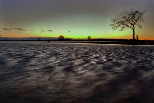 Fotografia przedstawia rozlewiska Biebrzy o zachodzie słońca. Fale na wodzie wytworzyły się pod wpływem bardzo silnego wiatru.