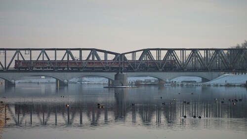 Zdjęcie ukazuje pociąg przejeżdżający przez most kolejowy nad Odrą we Wrocławiu.