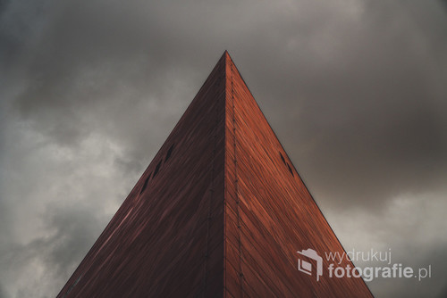 Element architektury Muzeum II Wojny Światowej w Gdańsku uchwycony na tle ciemnych chmur