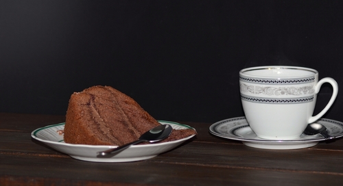 tort czekoladowo orzechowy z filiżanka kawy na blacie z desek tło czarne 