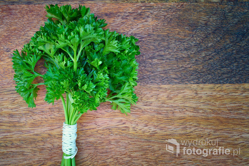  Bound sprigs of parsley lie on a wooden table. View from above.