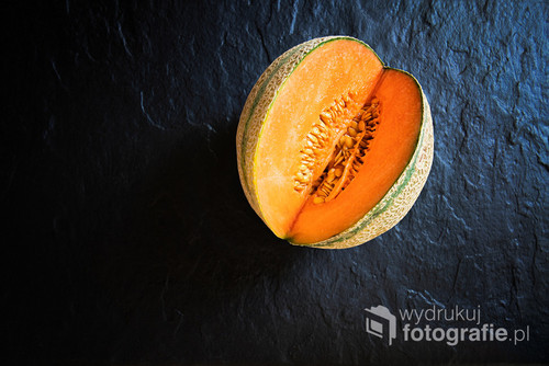 Small, cut melon lying on a stone slab. View from above. 