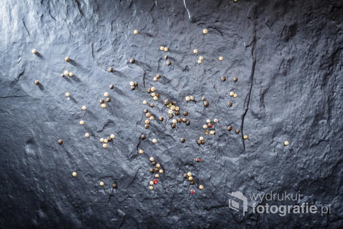 Pepper grainy, spilled on the surface of a stone slab. Cookbooks background.