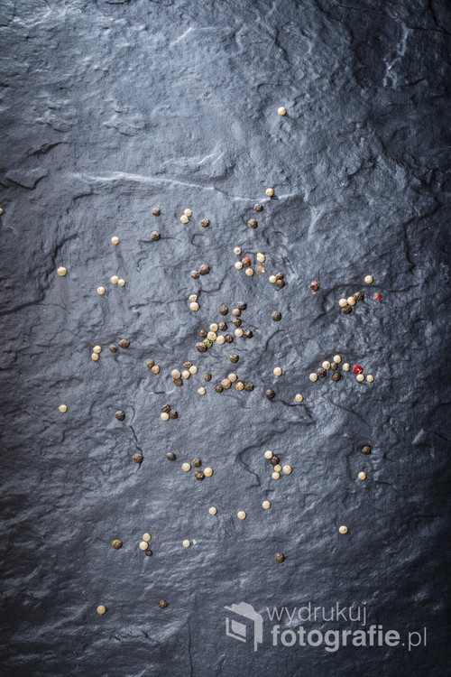Pepper grainy, spilled on the surface of a stone slab. Cookbooks background.