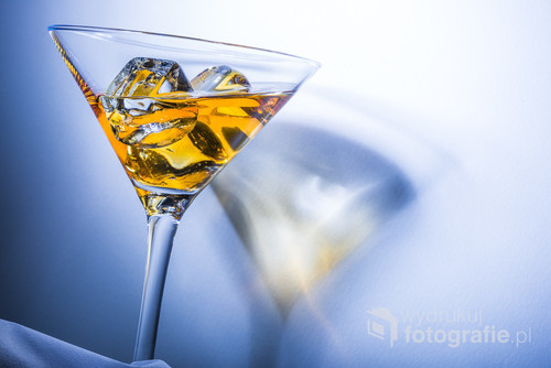 Orange liqueur into a martini glass. Multicolored reflections on the background.