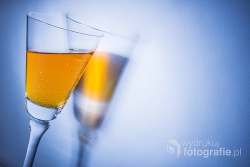 Orange liqueur into a glass. Multicolored reflections on the background.