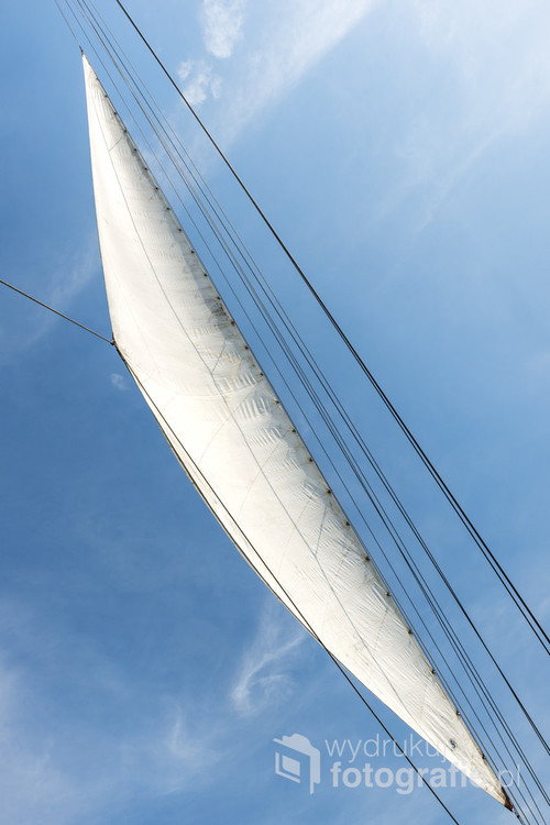 White sails on blue sky. Full sail exposed against a brilliant blue sky