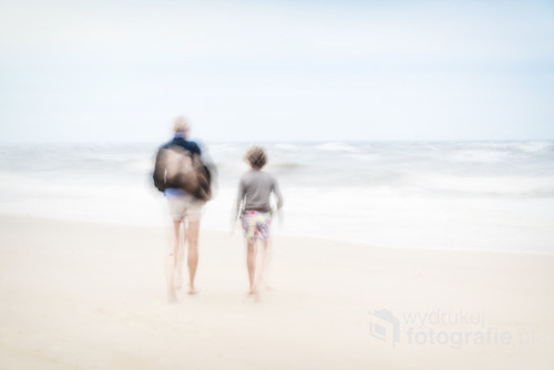 Two people on the beach during a storm. Blurred image.