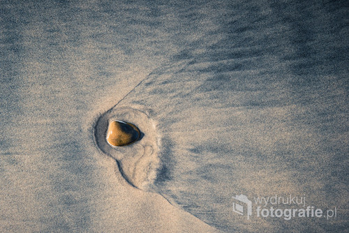 Small stone in beach sand. Abstract image.
I like walking on the beach and looking down. You can find incredible worlds there.