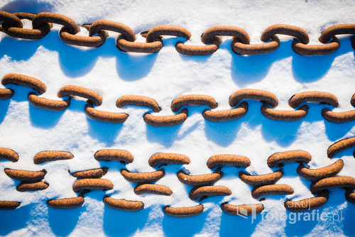 A steel, rusty chains covered in frozen snow. View from above. Abstract image. Photo was taken during visit in old abandoned Polish Szczecin Shipyard.