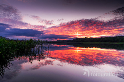 Zdjęcie przedstawia widok na jezioro Wigry o zachodzie słońca z jednego z pomostów w miejscowości Bryzgiel.