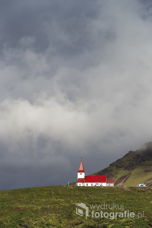 Zachmurzone niebo nad wzgórzem z charakterystycznym kościołem w islandzkim miasteczku Vik.